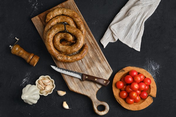 Horse meat sausage with garlic rolled on wooden cutting board
