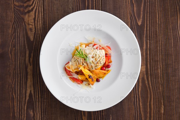 Top voew of fried turkey meat with roasted tomato and bell pepper served with parmesan