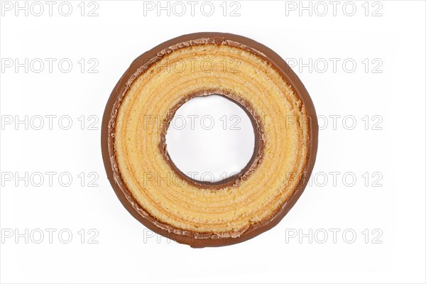 Round slice of traditional German layered winter cake called Baumkuchen glazed with chocolate showing thin layers inside of cake isolated on white background