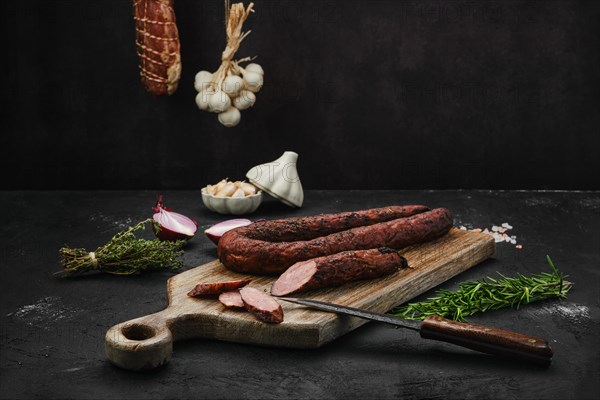 Smoked pork sausage with spices on wooden cutting board