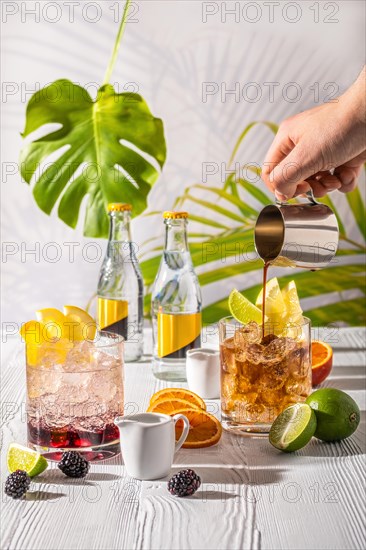 Espresso-tonic refreshing drink with different fruits and syrups on wooden table under morning sun