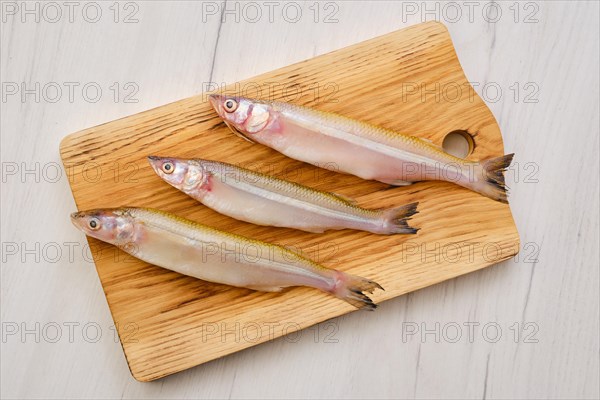 Top view of raw fresh smelt fish on wooden cutting board