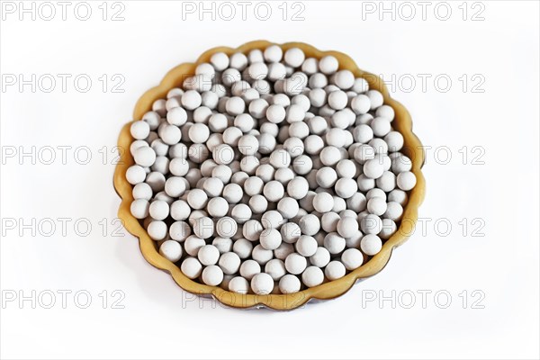 Top view of unbaked tart filled with ceramic pie weights used to keep crust from shrinking during blind baking