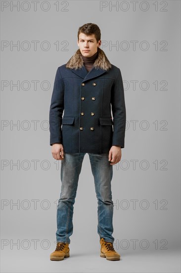 Full length portrait of handsome man in warm winter coat posing in studio