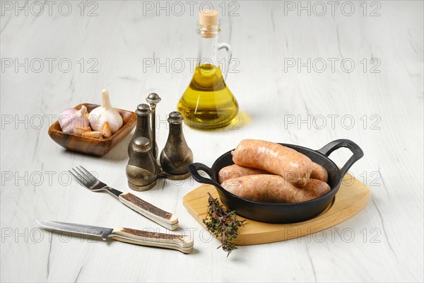 Raw traditional homemade British banger pork sausage in cast-iron skillet ready for frying