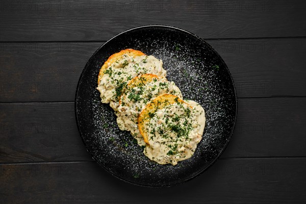 Top view of potato patty with fried boletus and creamy sauce on a plate