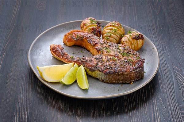 Plate with baked salmon steak with hasselback potatoes