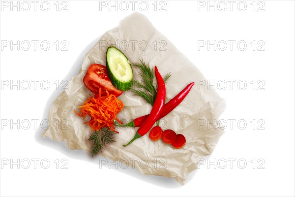 Colorful vegetables on crumpled parchment for baking isolated on white. Ingredients for salad