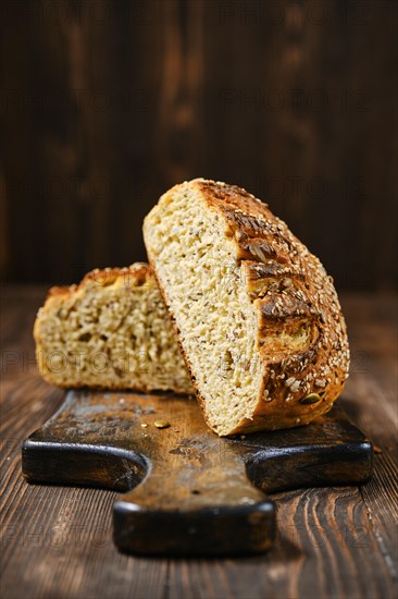 Fresh oats bread with sunflower seeds and sesame on wooden table