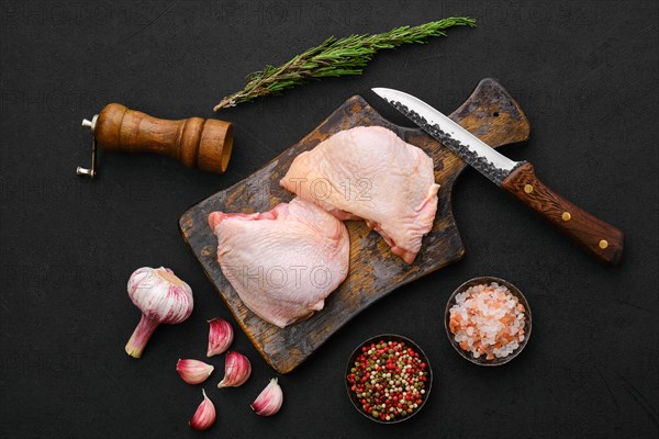 Overhead view of raw chicken thighs on black background ready for cooking