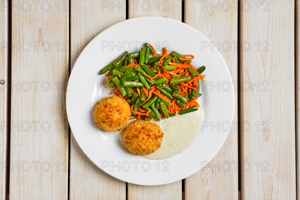Top view of meatballs in breading served with green bean and spicy carrot