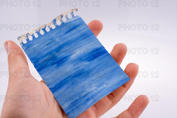 Hand holding painted torn note paper on white background