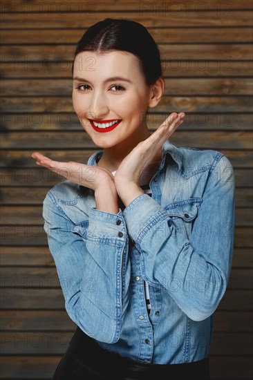 Pretty fashion model in jeans shirt with tan makeup and red mat lips on wooden background