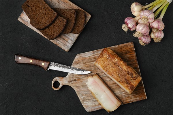 Overhead view of smoked fat with brown bread on wooden cutting board