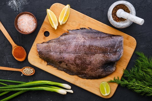 Top view of raw fresh halibut without head on wooden cutting board