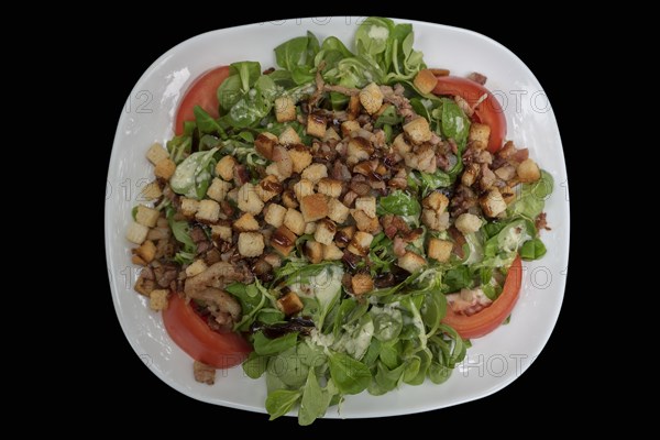 Lamb's lettuce with ham and croutons on a black background