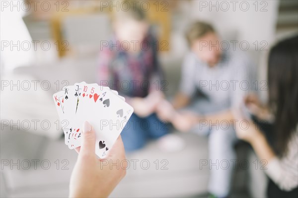 Crop person with cards playing with friends