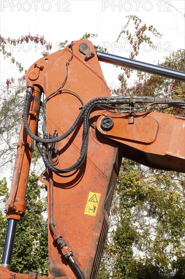 Orange hydraulic excavator arm of an excavator on a construction site