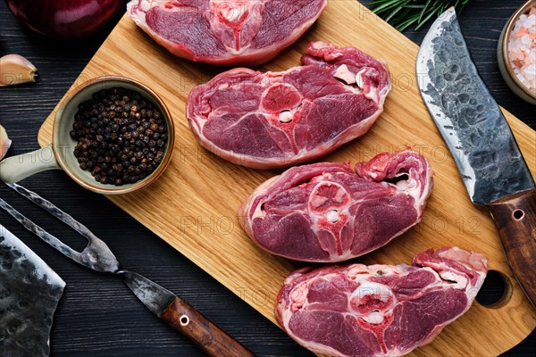 Overhead view of chopped fresh lamb shank with spice on cutting board with spice