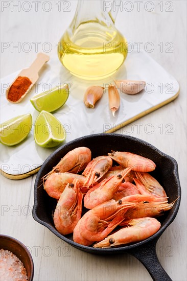 Cast iron skillet with steamed unpeeled shrimps with spice