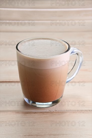 Transparent cup with hot cocoa chocolate on wooden table