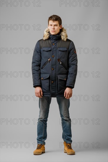 Full length portrait of handsome man in warm winter coat posing in studio