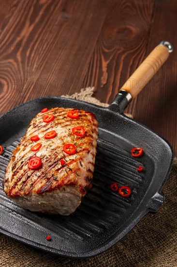 Grilled striploin on cast iron skillet and fried eggplant on wooden background