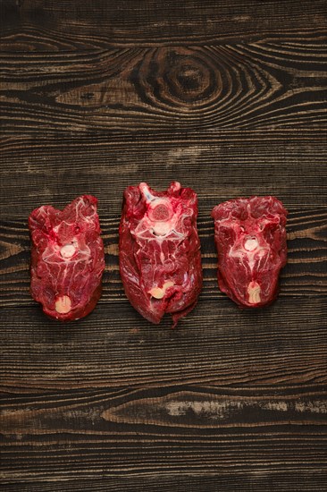 Overhead view of raw fresh deer neck over dark wooden background