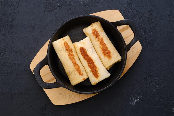 Top view of thin pancakes stuffed with turkey meat in cast iron skillet