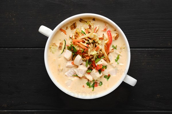 Top view of creamy chicken soup puree with fried carrot and onion