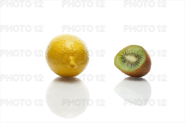 Lemon and kiwi with reflection on white glass table