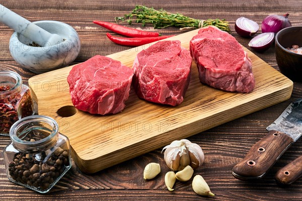 Marinated raw beef steak with spice on wooden table