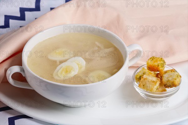 Plate with chicken clear broth with quail eggs and crackers