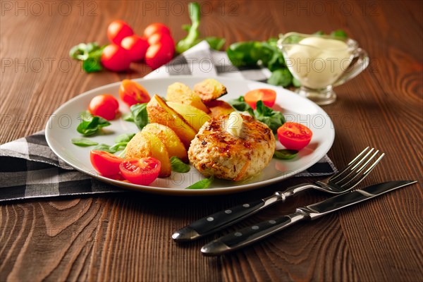 Fried chicken cutlet with potato slices served with tomato cherry and corn salad. Traditional belorussian food