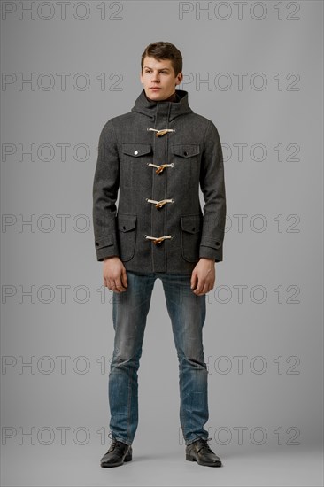 Full length portrait of handsome man in warm woolen coat posing in studio