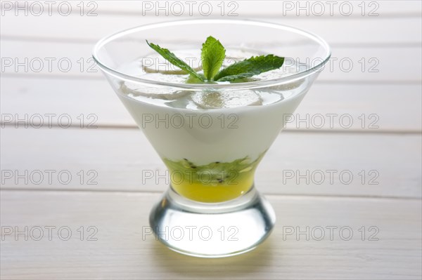 Glass with yogurt with banana and kiwi with honey decorated with mint leaf on top