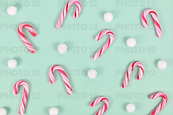 Small red and white striped Christmas candy cane sweets on mint green background