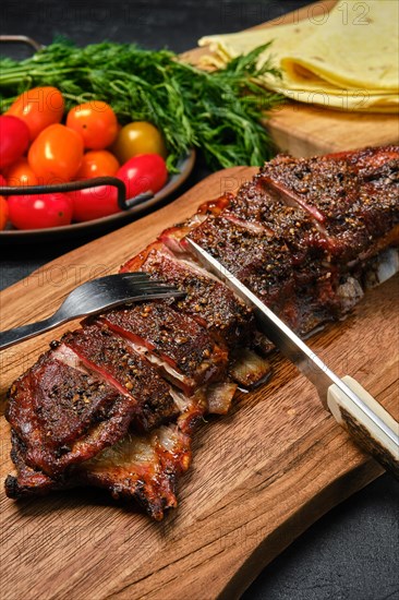 Close up view of grilled lamb breast and flap on wooden cutting board