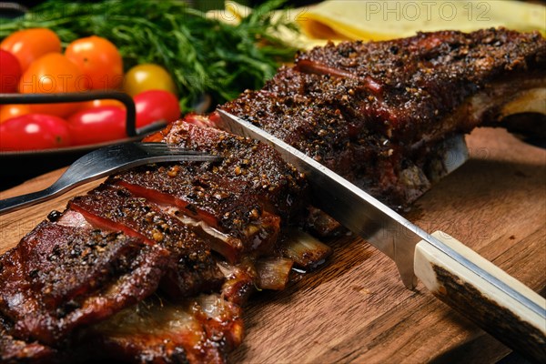 Close up view of grilled lamb breast and flap on wooden cutting board