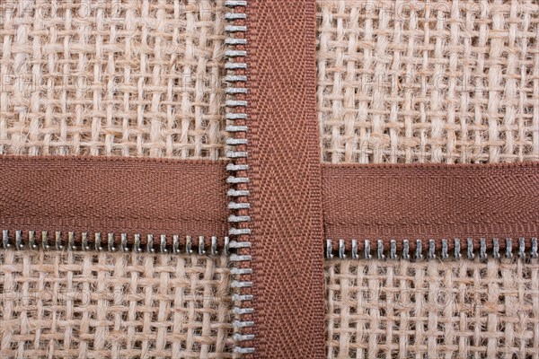 Parts of the brown color zipper on linen canvas background