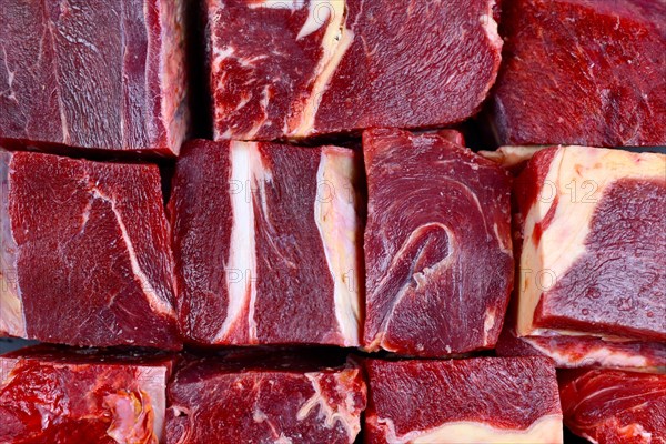 Big chunks of streaked red raw horse meat with lots of fat used for raw feeding of dogs or cats