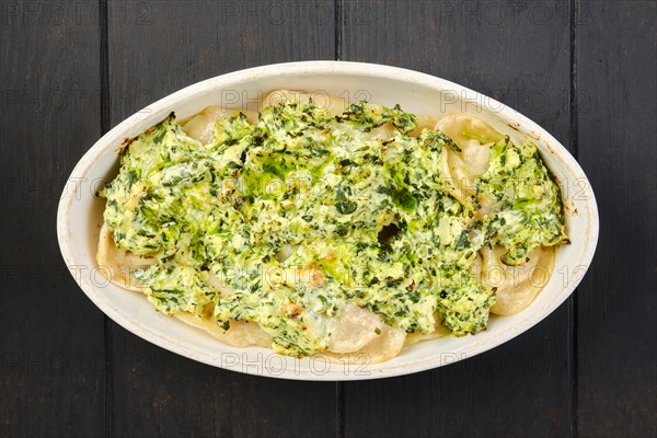 Overhead view of meat dumplings with spinach and cheese sauce baked in oven