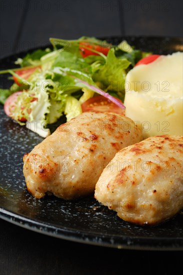 Closeup view of meat cutlet with mashed potato and fresh vegetables on a plate