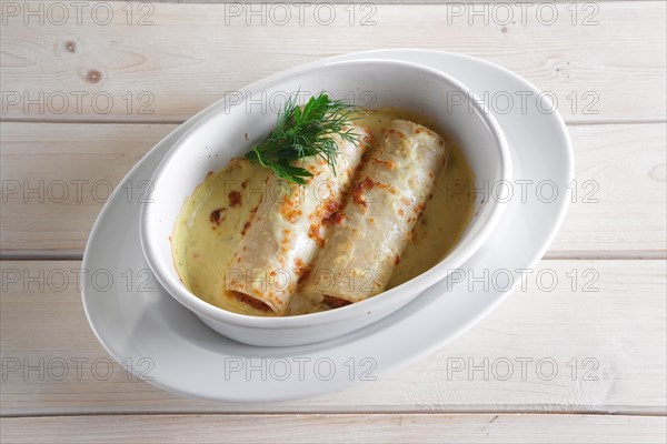 Thin pancakes with stuffing baked in oven with melted cheese
