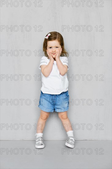 Two years old girl in white t-short and jeans shorts posing in studio