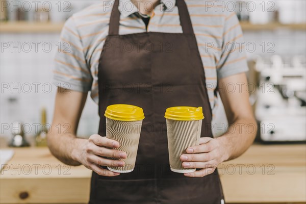 Crop barista with hot drinks