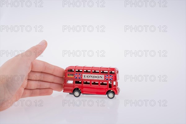 Child hand playing with London double decker bus model on white background