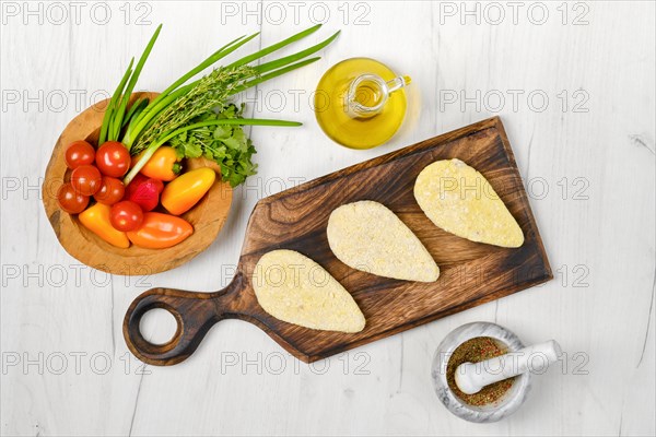 Top view of semifinished homemade zander cutlet on a wooden serving board