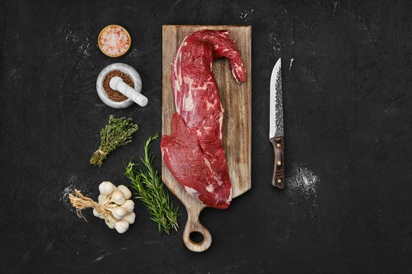 Overhead view of raw beef tri-tip loin on wooden cutting board