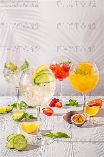 Assortment of cold lemonades in wine glasses on white wooden table in morning sunlight